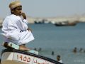 Gamin méditant sur une barque sur la plage d'Asaylah. Cote orientale d'Oman. Sultanat d'Oman